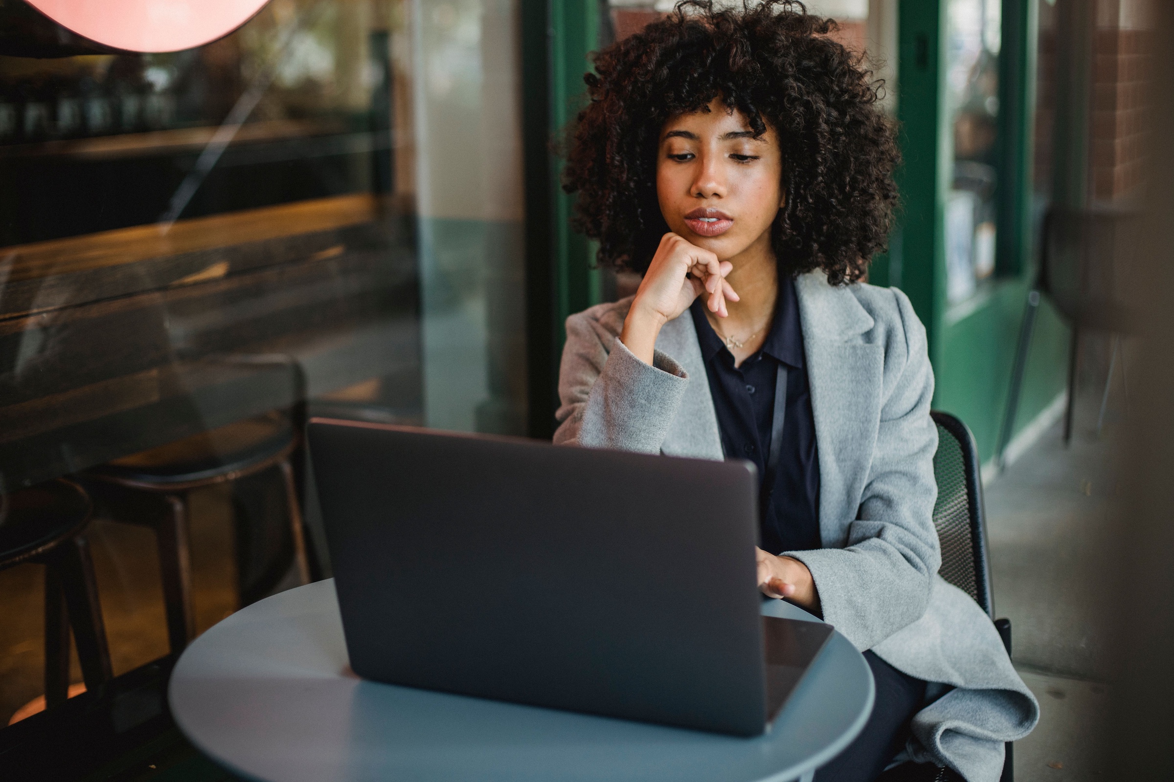 professional woman sitting at a cafe table working on her laptop